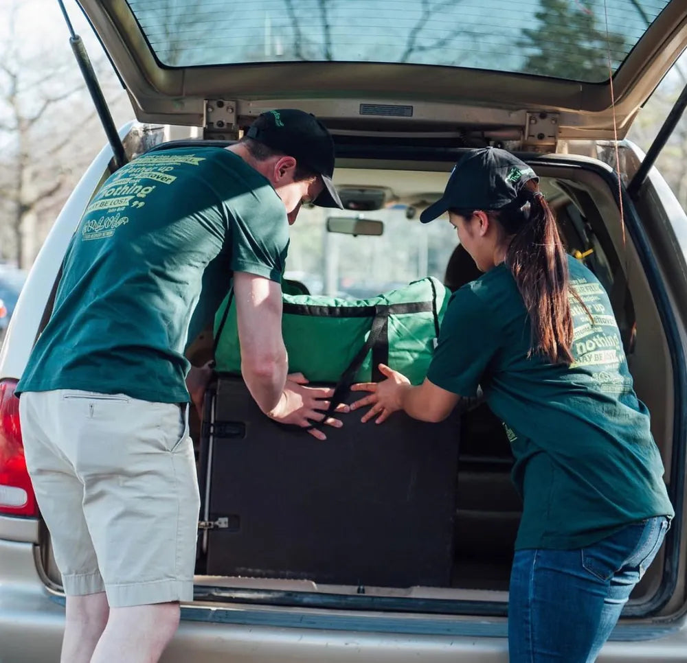 Two Food Recovery Network volunteers loading rescued food into a car