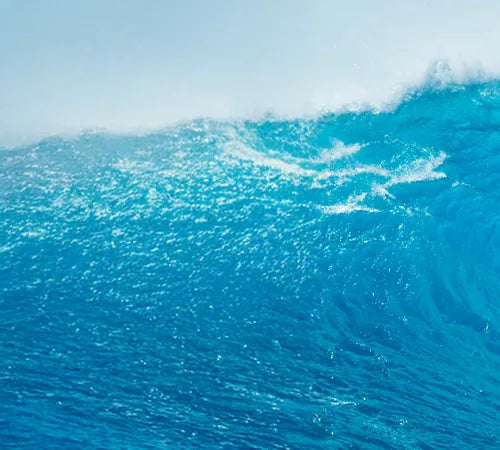 A deep blue ocean wave breaking
